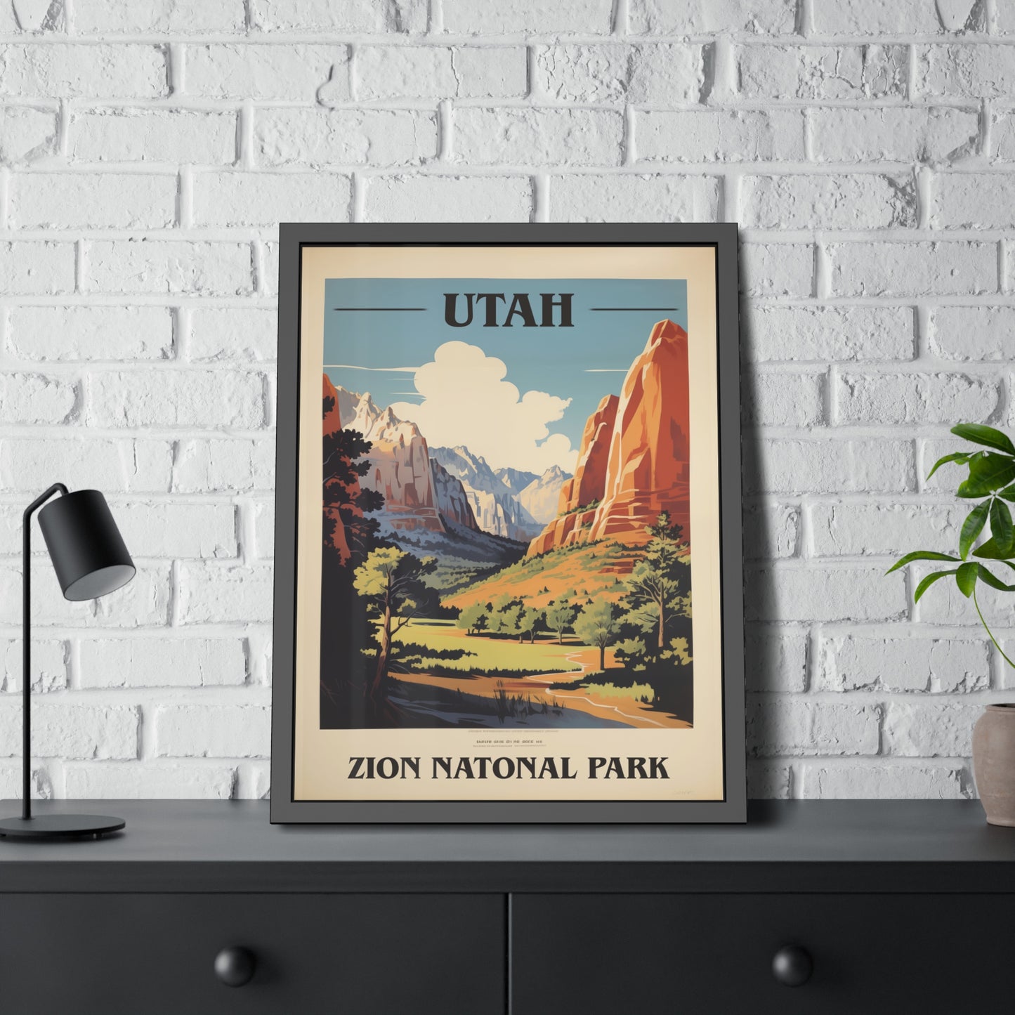 Framed vintage Utah Zion National Park travel art print on a dark shelf beside a plant