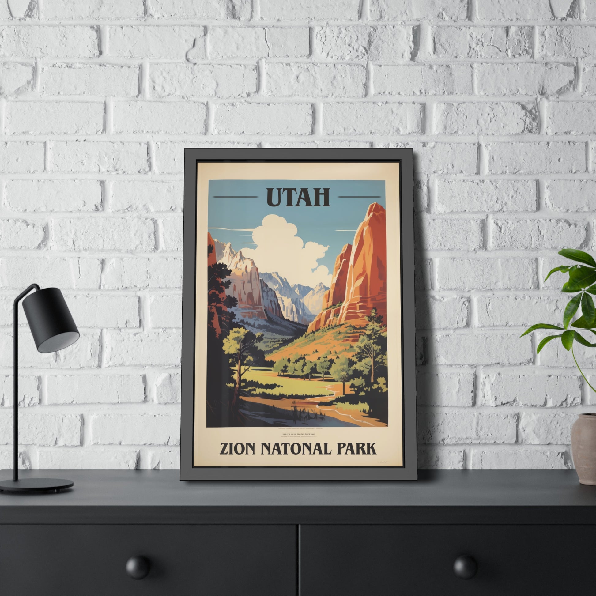 Framed vintage Utah Zion National Park travel art print on a dark shelf beside a plant